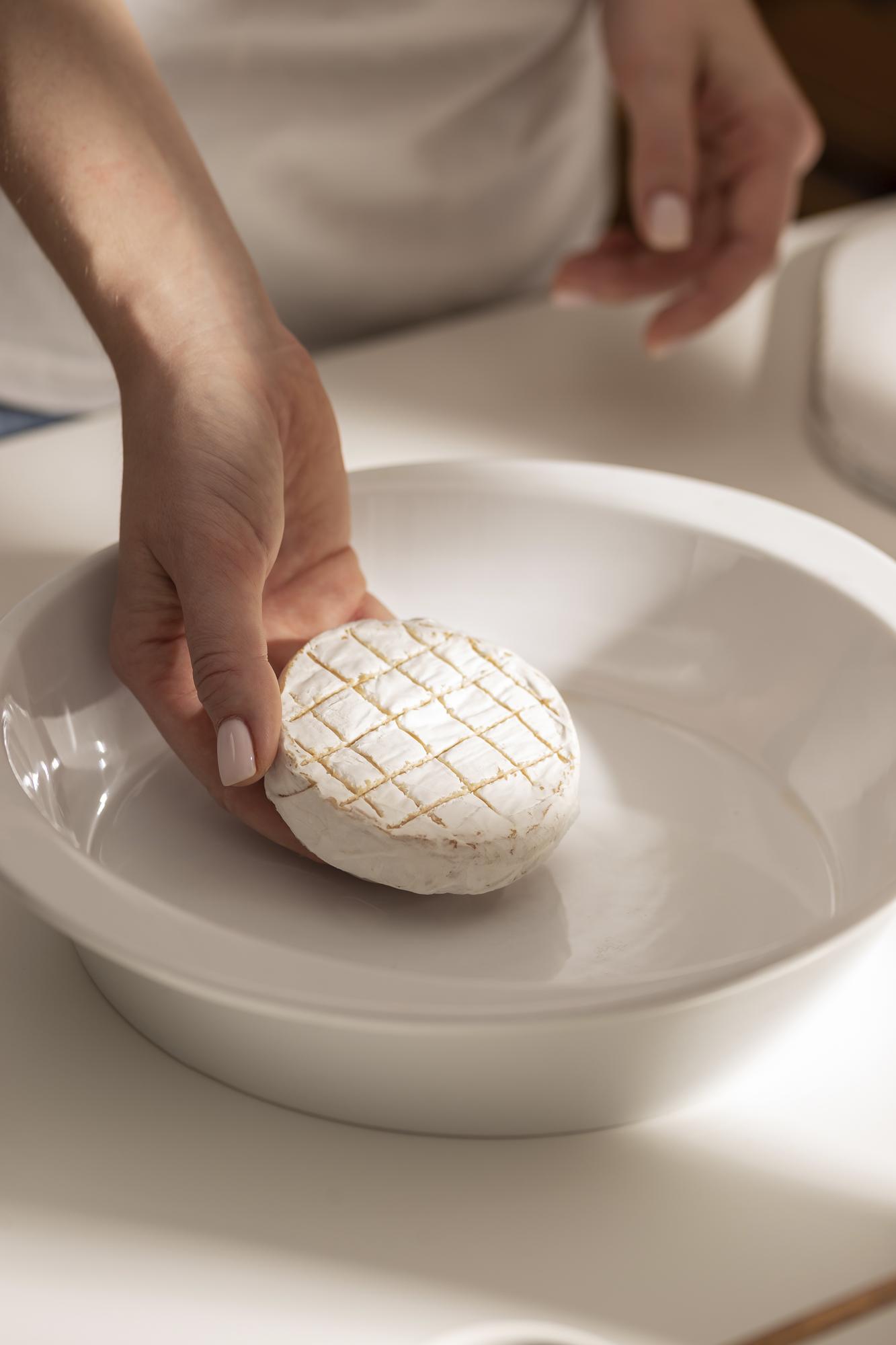 hands plating a simple composed dish on a ceramic plate